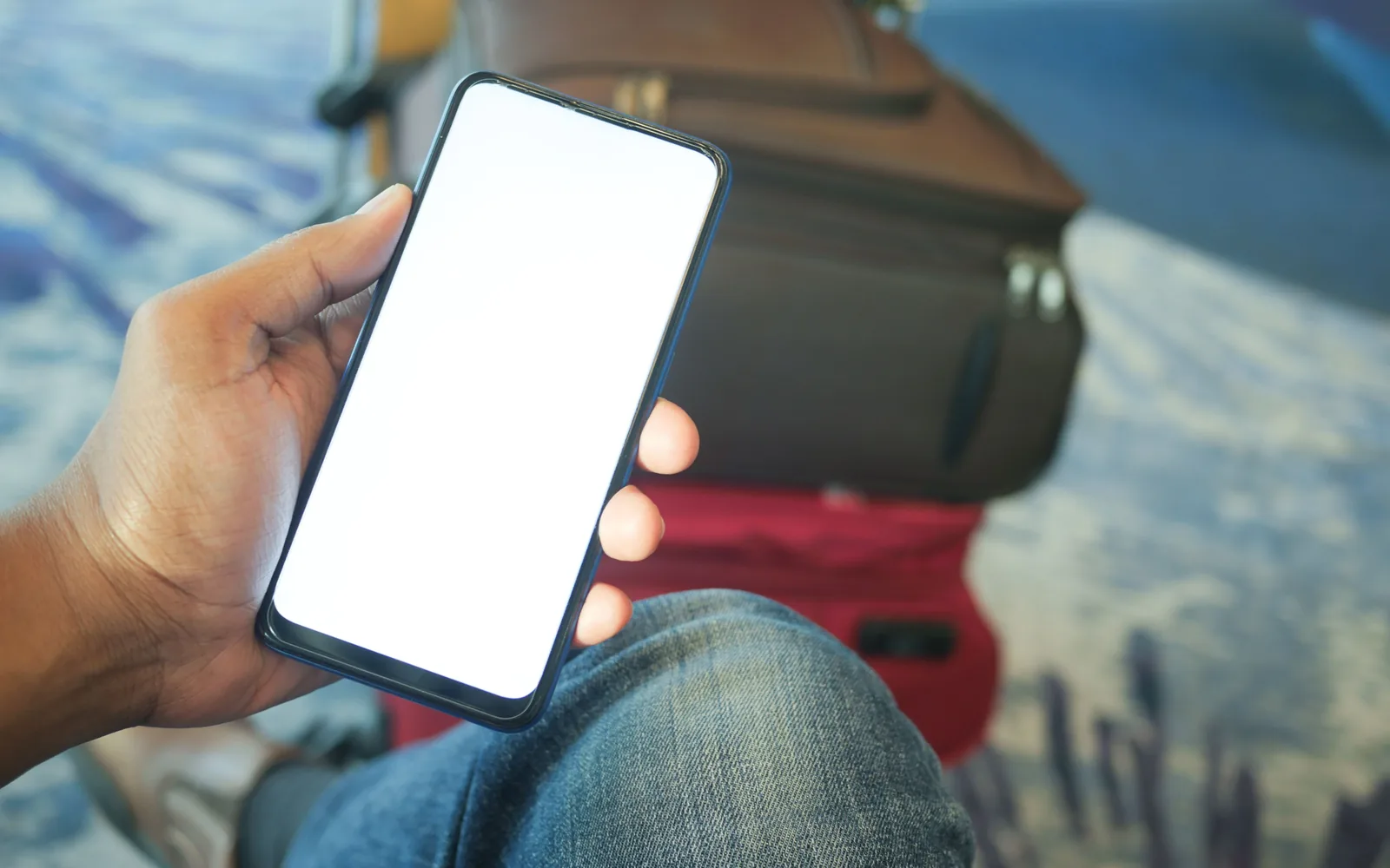 Traveler holding a phone beside luggage