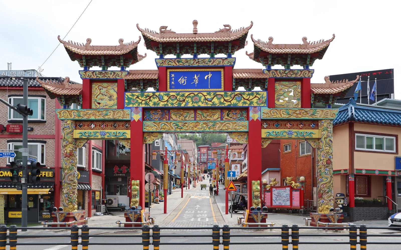 Ornate red-and-gold gate at Incheon Chinatown with the main street rising behind it