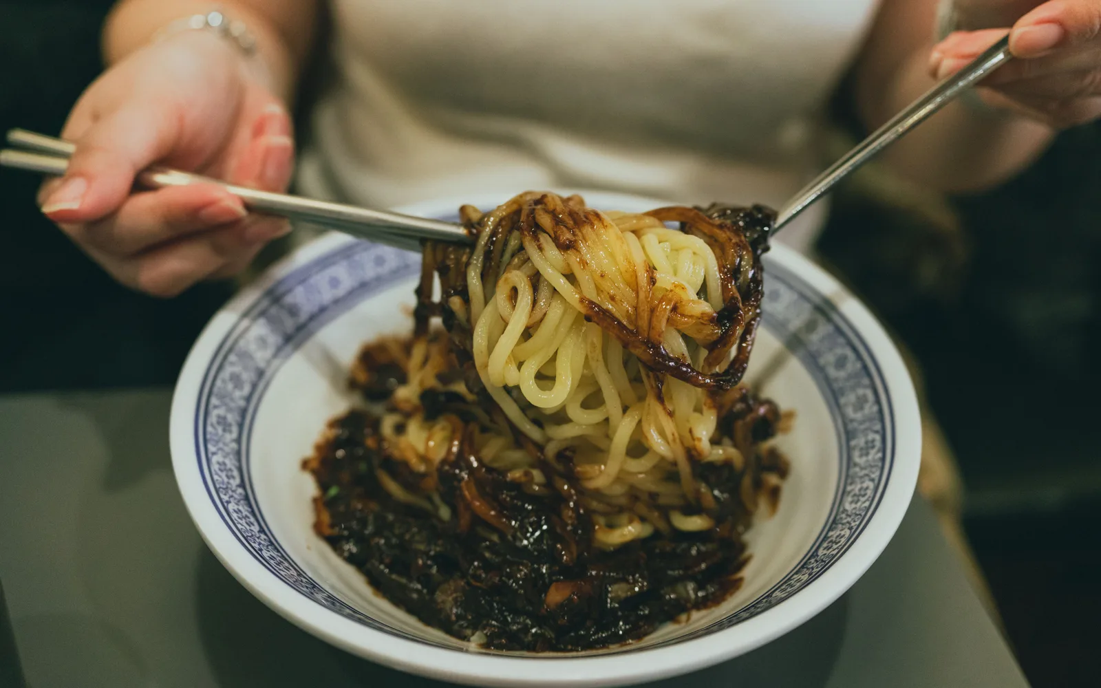 Diner lifting black-bean-sauce noodles from a bowl of jjajangmyeon
