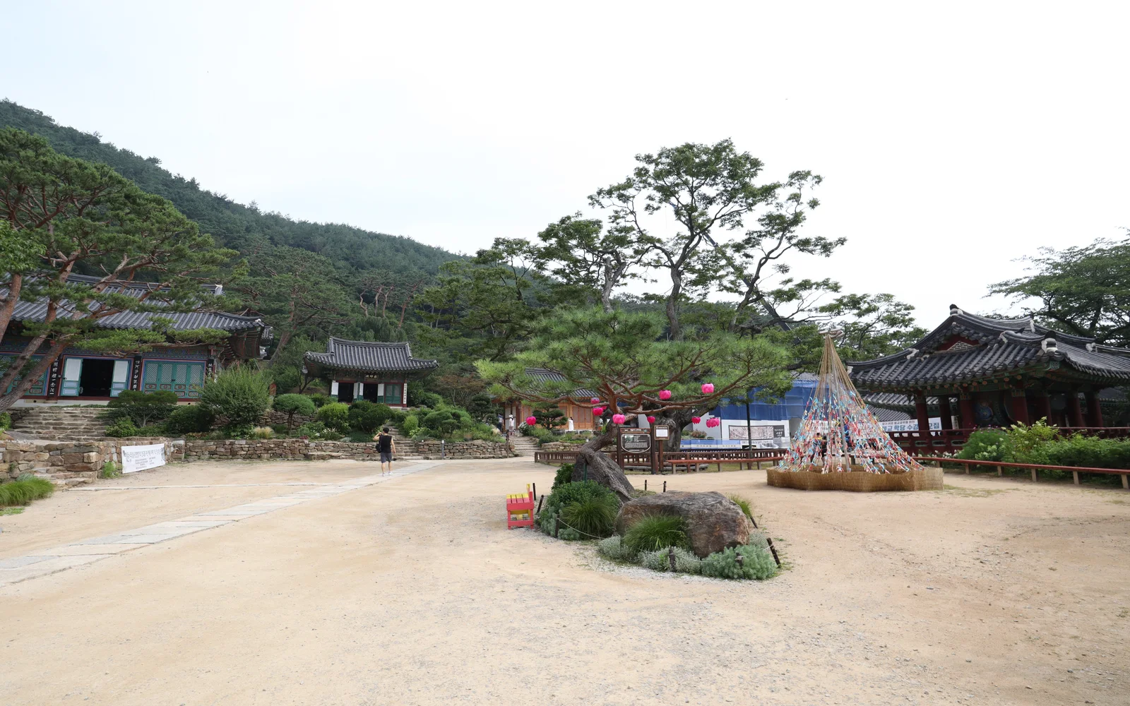Traditional tiled buildings in the courtyard of Jeondeungsa Temple below a wooded hill