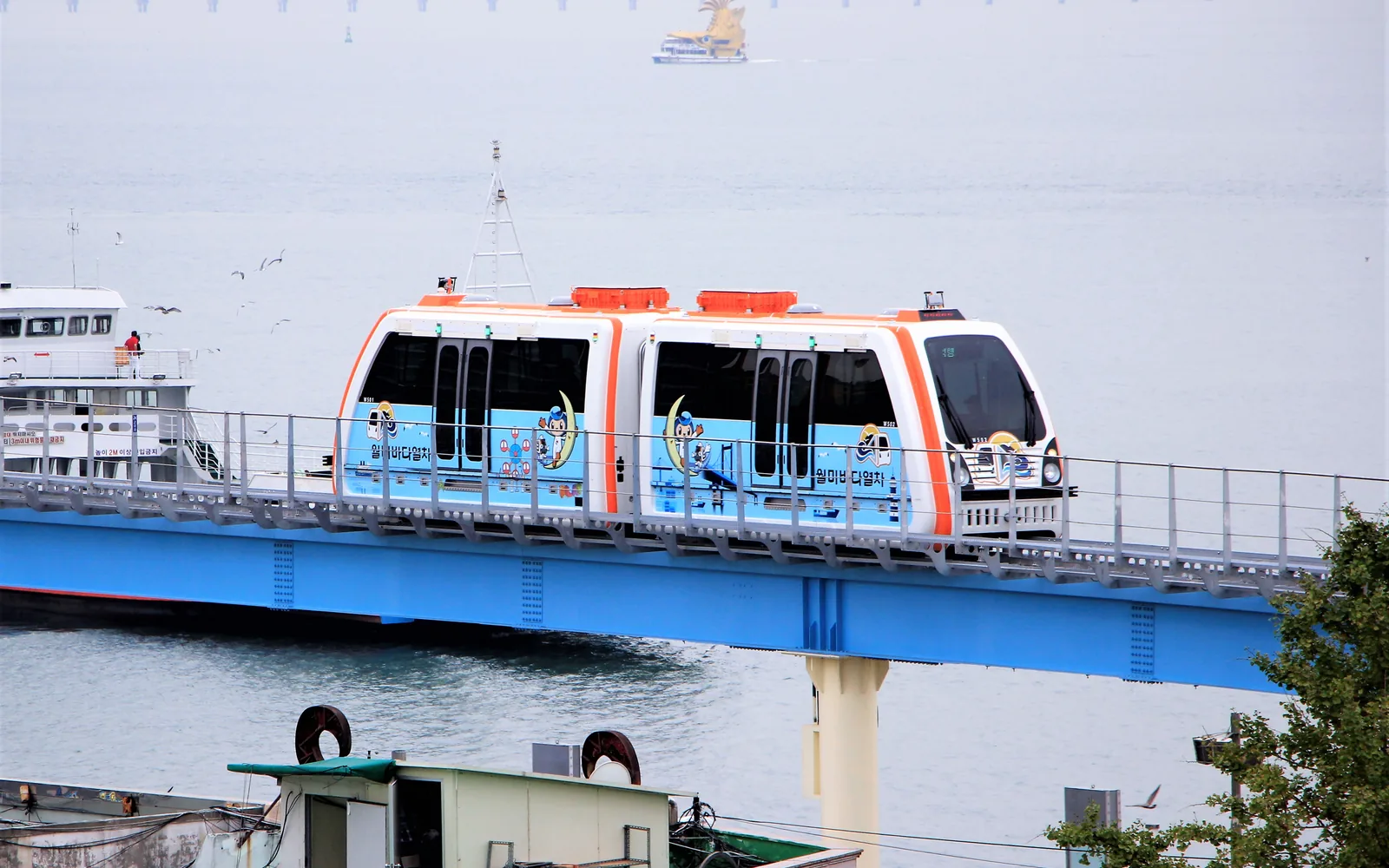 Wolmi Sea Train car traveling on an elevated guideway beside the water