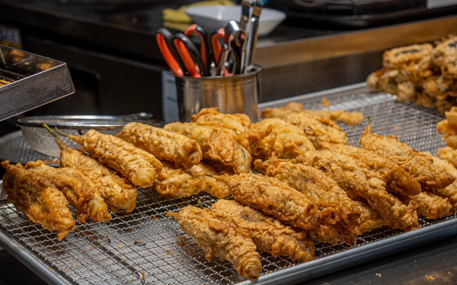 Assorted battered snacks cooling on wire racks at a Korean market stall