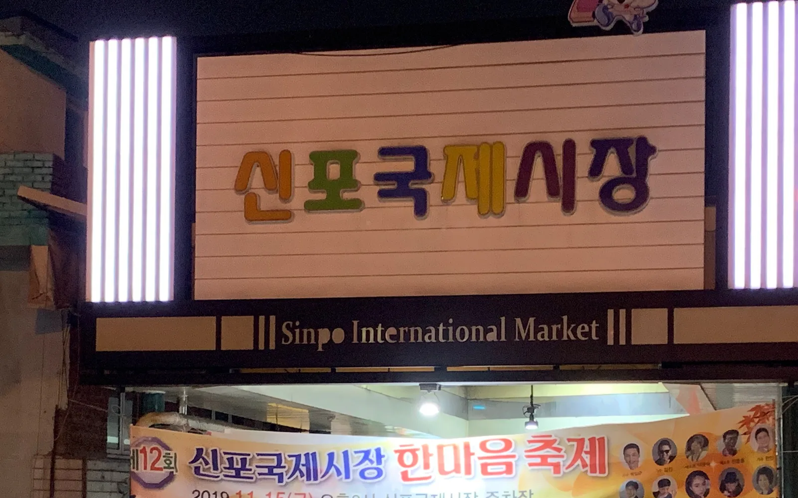 Illuminated Korean and English sign above an entrance to Sinpo International Market at night