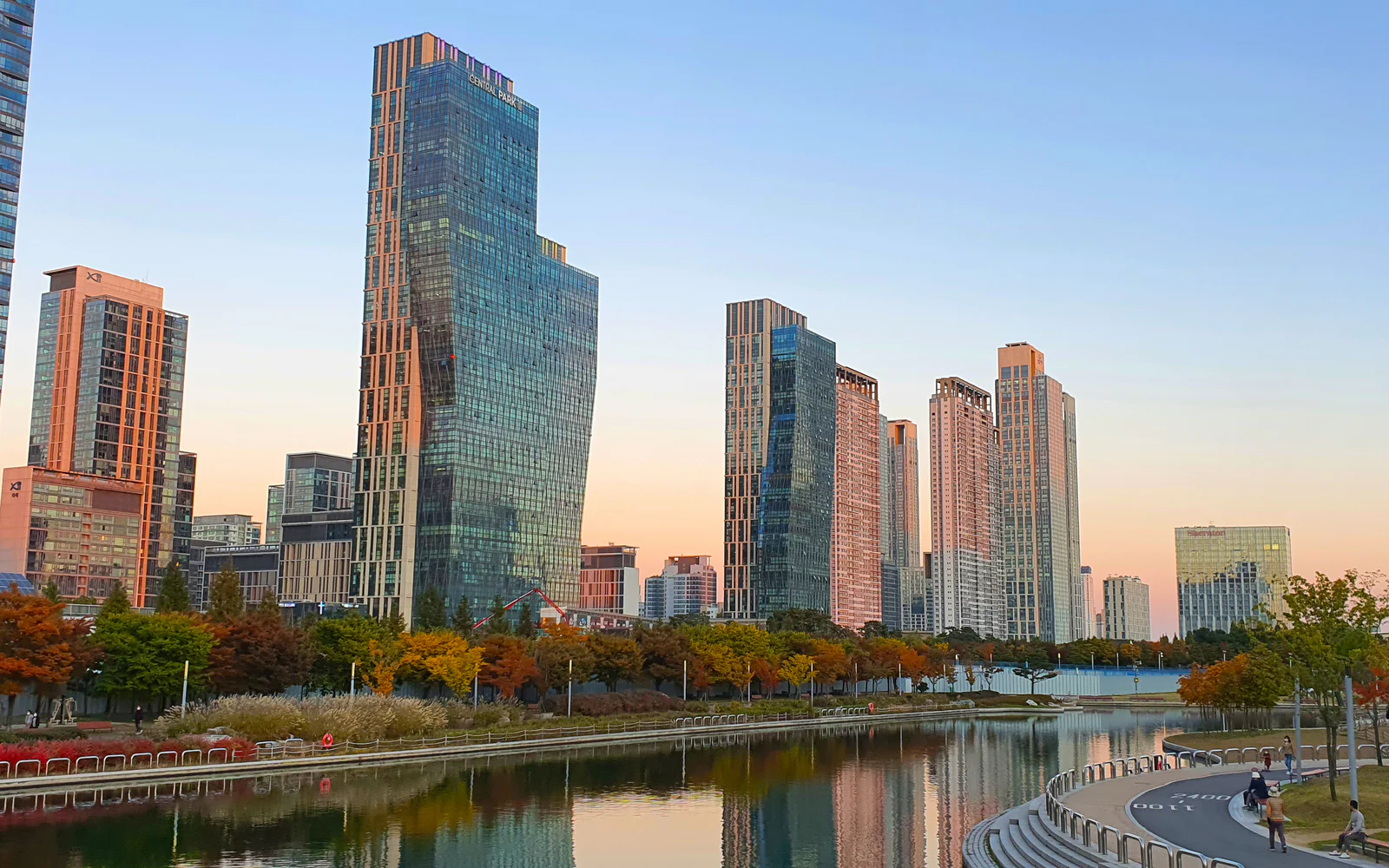 Autumn trees and high-rise buildings reflected in the water at Songdo Central Park