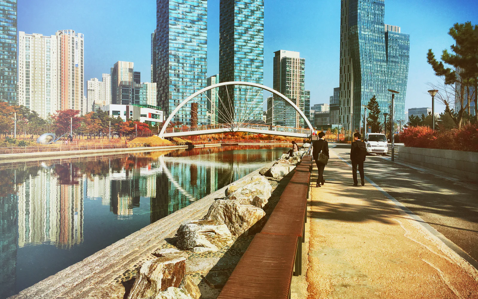 Waterfront walking path leading to an arched bridge in Songdo Central Park