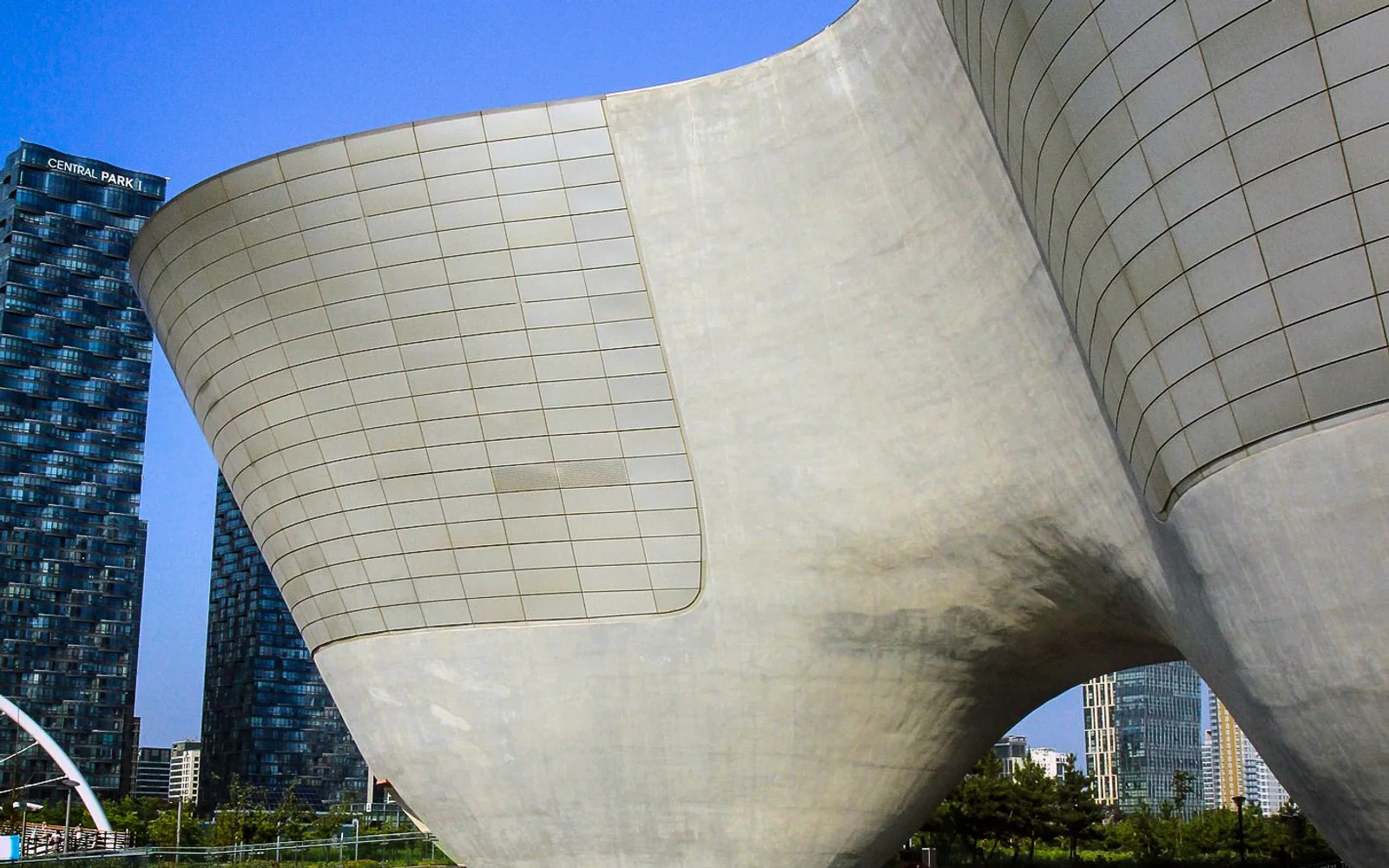 Curved exterior forms of Tri-Bowl with Songdo towers in the background