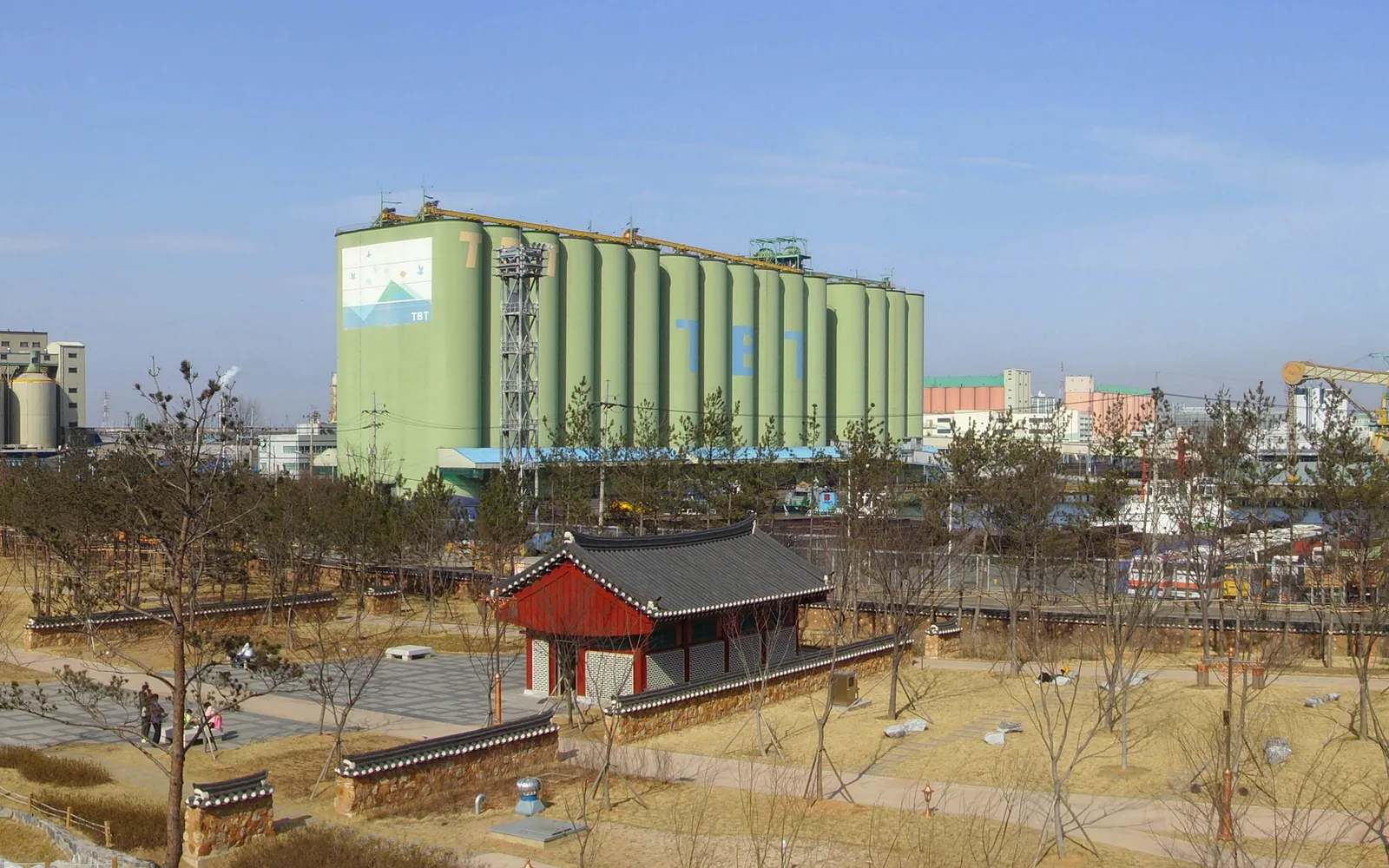 Traditional garden pavilion and paths in Wolmi Park with Incheon port buildings behind them